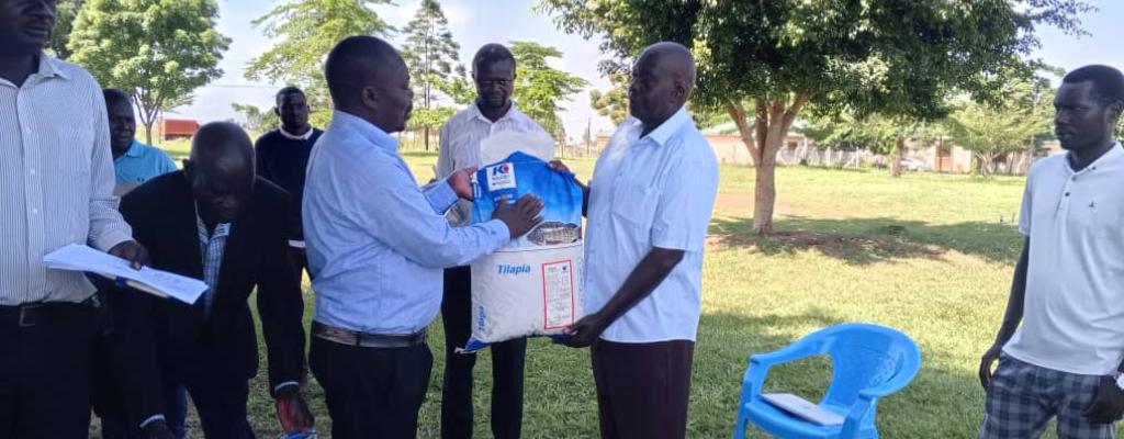 The Assistant RDC distributing the catfish Fingerlings and the fish feeds to fish farmers in nwoya District